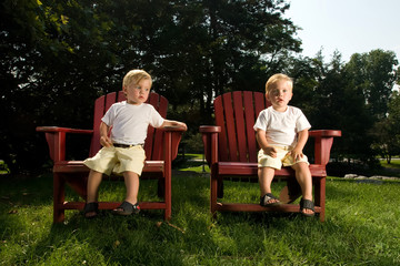 Twin Baby Brothers Sitting on red Lounge Chairs enjoying summer