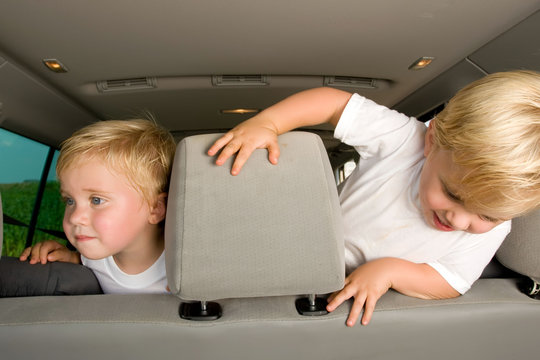 Twin Little Boys In The Backseat Of A Car