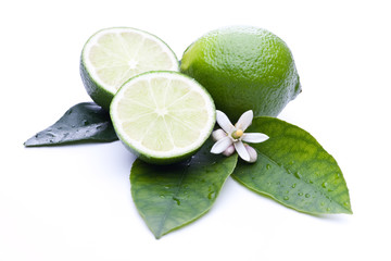 Ganze und halbierte Limette auf Blättern