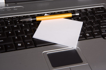 Note pad and a pen on laptop keyboard