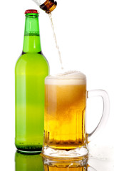 Glass of beer in the front with foam with green bottle of beer