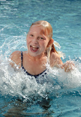 Fototapeta na wymiar Mädchen im Grundschulalter fröhlich spritzend im Pool