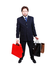 Young attractive man wearing suit and holding shopping bags