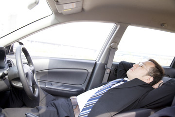 車内で仮眠をとるビジネスマン