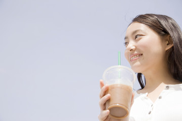 アイスコーヒーを飲みながら歩く女性