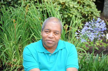 African american man sitting in a flower garden.