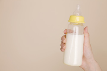 哺乳瓶に入ったミルクを持つ母親の手