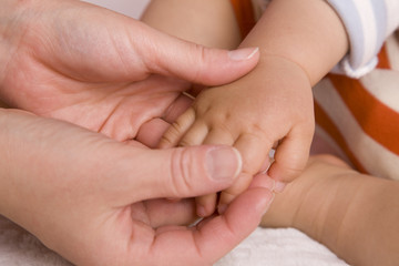 母親に手を握られる赤ちゃん