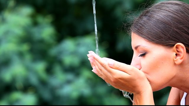Jeune femme buvant de l'eau &agrave; une source