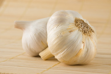 Two garlic heads on a bamboo mat.