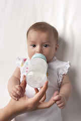 Babygirl drinks from a baby-bottle