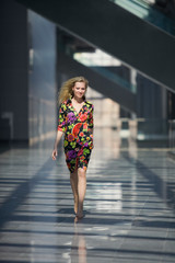 blond woman in colourful dress going through the corridor
