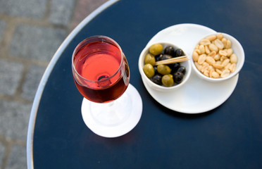 Street cafe table with aperitif and nibbles. Focus on glass