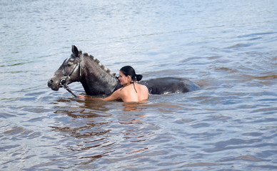 Fototapeta premium woman swimming winth her black stallion