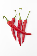 Four red hot peppers on white background