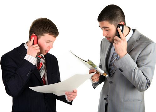 Two young businessmen working and telling the phone