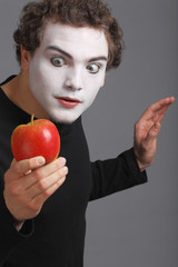 Portrait of Mime with red apple on grey background