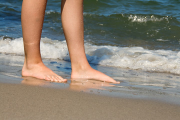 Legs of young girl standing at the beach