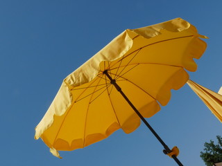 Gelber Sonnenschirm vor blauem Himmel