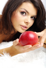 Portrait of  woman sitting on bed and eating fresh red apple