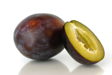 A whole and a bisected blue plum