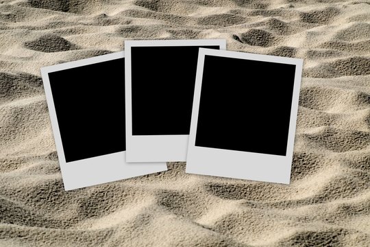 Empty photo frames  on sand background