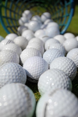 Golf balls pouring out of basket onto grass