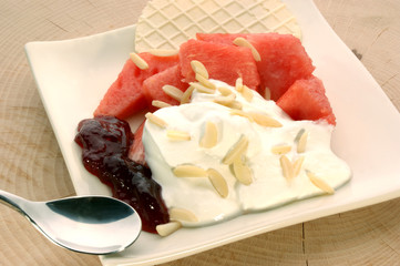 Melon, wafer and cream on a white plate