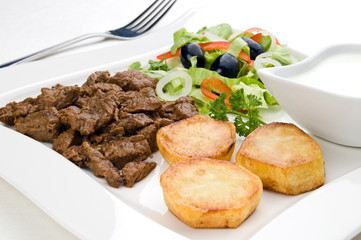 Grilled meat with baked potatoes and vegetable salad