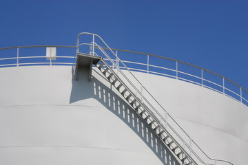 Oil reservoir detail with access ladder against a blue sky