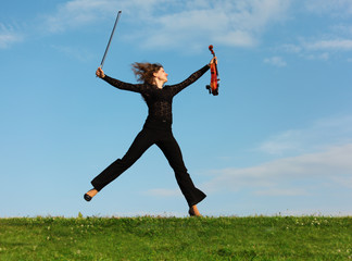 girl with violin jumps on grass against  sky © Pavel Losevsky