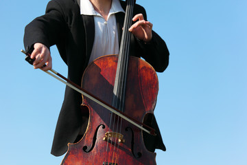 close-up musician plays violoncello against  sky © Pavel Losevsky