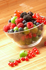 Fruit mix in the glass container, on a table from straw