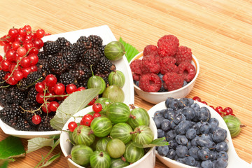 Berries in plates, on a table, among green leaves