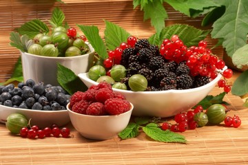 Berries in plates, on a table, among green leaves