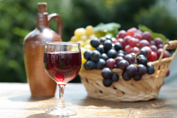 Glass of red wine and grapes in a basket