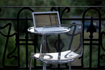 weißer Laptop auf rundem Glastisch und Plexiglasstuhl auf Balkon - 16341317