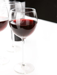 Glasses of red whine on white table cloth.