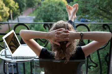 junge blonde Frau entspannt, Füße hoch, vor Laptop auf Balkon - 16347339