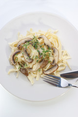 Pasta with mushroom and herbs on a white plate