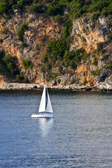 White Sailboat Past Golden Cliffs