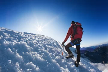 Foto auf Acrylglas Bergsteigen Bergsteiger erreicht die Spitze eines hohen Berggipfels.
