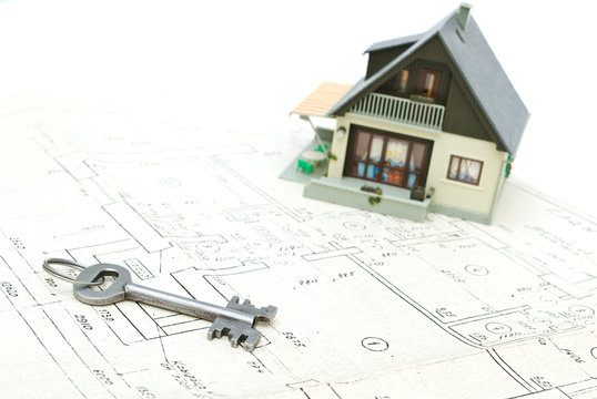 A model home and house key on architectural plans