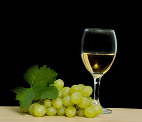 Goblet with wine and grapevine isolated on black background