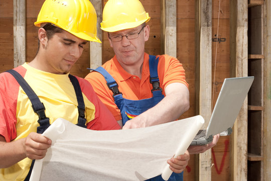 two workers with a notebook on a construction site