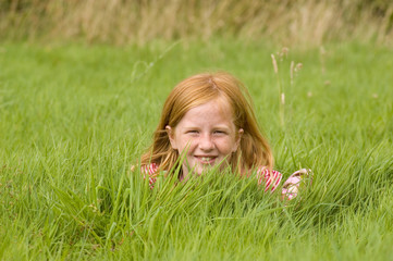 red head girl is laying in long grass