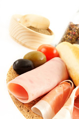 Different type of salami, ham and vegetables on wooden board