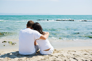 A couple sitting on beach with woman
