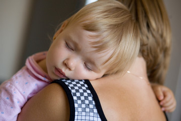 child sleeps on the shoulder of his mother