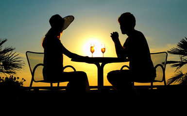 Obraz na płótnie Canvas Woman and man sit at a table on a sundown